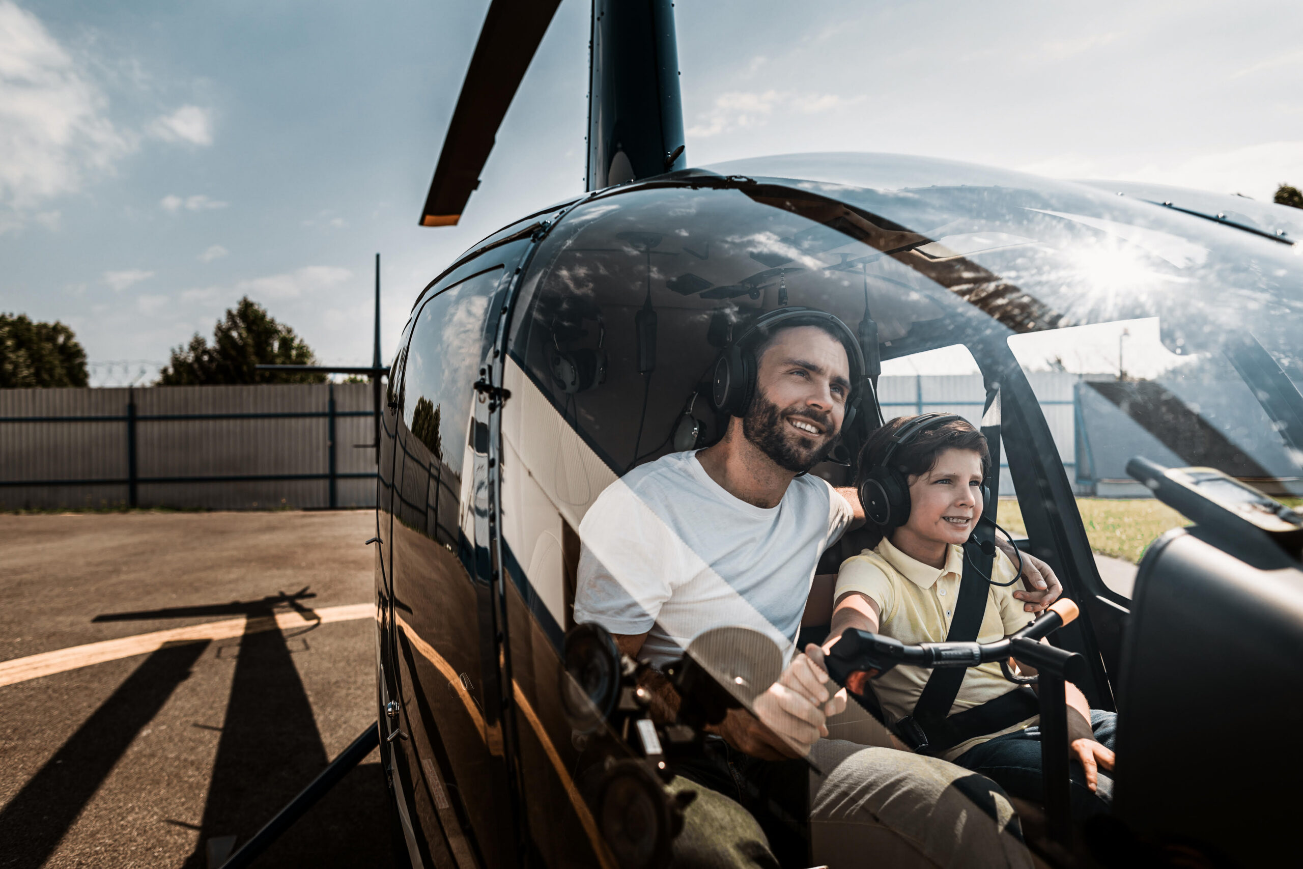 Portrait of happy unshaven father embracing glad boy while controlling helicopter with him. They sitting in cabin of it while talking. Optimistic parent and guy wearing earphones with microphones during sunny day SSUCv3H4sIAAAAAAAEAJ2RwY6DIBCG75vsOxjOmoi2qPsqzR6mwNpJrTSAbZrGdy+IJHPeG//3M8P8w/v7qyjYGRxK9lO8owoap2lx3oJHMwdclzvXCr2xCFOEka2bw5wHvzjtYosdSfB6DHcT3OvzO6eki2xsZqgIFmMlYW45byyjtfx3ZTr85igw6lm+toFJEKsnDSnIKV1l16fX9kajPVBpQzQsCg1J+TASpljQks53ixLnkZQZf9GWbiys3NwImI3fJtmDMRVWGiVvedf3gxiOgh9Ez+uO5W8w8oqKzpp+5oLBsi/CUcVOjaiVaHhXtULU1QFUWw31n6g41/LYDgL6hocNrh/mV8YiJgIAAA==
